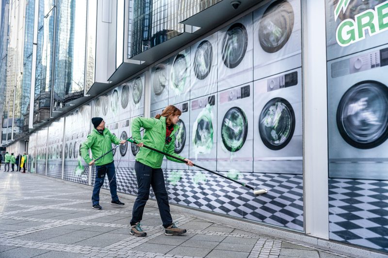 Hohe Boni für ein grünes Mäntelchen: Greenpeace-Aktive wandeln die DWS-Firmenzentrale in Frankfurt in einen Greenwash-Salon um