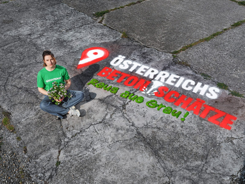Eine Aktive von Greenpeace Österreich protestiert gegen unnötig versiegelte Flächen.